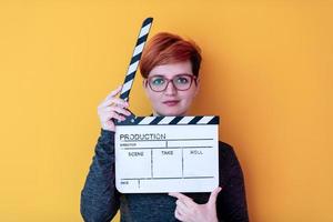 woman holding movie clapper against yellow background photo