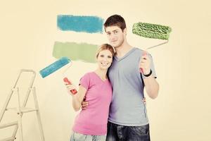 pareja feliz pintando una pared en su nuevo hogar foto