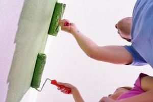 happy couple paint wall at new home photo