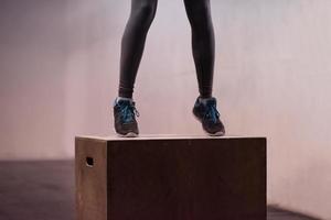 black woman is performing box jumps at gym photo