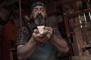 maestro de artesanía de cucharas en su taller con productos de madera hechos a mano y herramientas de trabajo foto