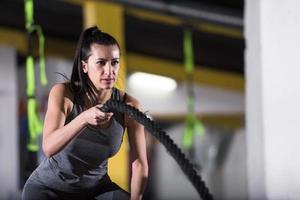 athlete woman doing battle ropes cross fitness exercise photo