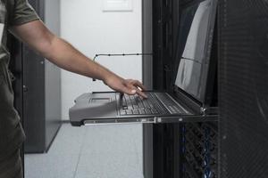 Close up on Data Center Engineer hands Using keyboard on a supercomputer Server Room Specialist Facility with Male System Administrator Working with Data Protection Network for Cyber Security. photo