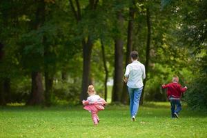 familia feliz jugando juntos al aire libre en el parque foto