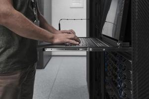 Close up on Data Center Engineer hands Using keyboard on a supercomputer Server Room Specialist Facility with Male System Administrator Working with Data Protection Network for Cyber Security. photo