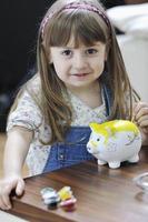 cute little girl painting piggy bank photo
