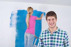 pareja feliz pintando una pared en su nuevo hogar foto