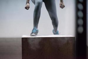 black woman is performing box jumps at gym photo