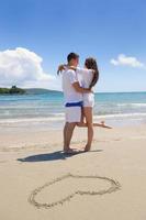 romantic  couple in love  have fun on the beach with heart drawing on sand photo