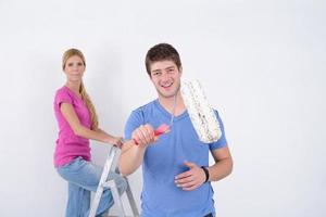 pareja feliz pintando una pared en su nuevo hogar foto