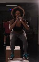 black female athlete is performing box jumps at gym photo