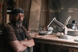 Spoon master in his workshop with wooden products and tools photo