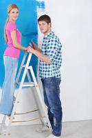 pareja feliz pintando una pared en su nuevo hogar foto