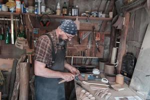 Spoon master in his workshop with wooden products and tools photo