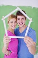 pareja feliz pintando una pared en su nuevo hogar foto