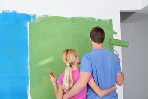 pareja feliz pintando una pared en su nuevo hogar foto