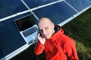 engineer using laptop at solar panels plant field photo