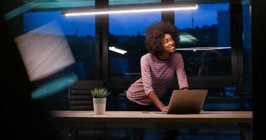 black businesswoman using a laptop in night startup office photo