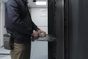 Close up on Data Center Engineer hands Using keyboard on a supercomputer Server Room Specialist Facility with Male System Administrator Working with Data Protection Network for Cyber Security. photo