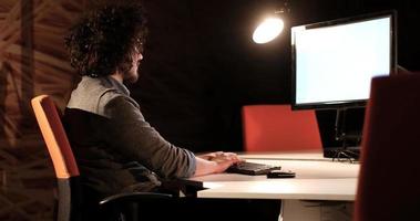 man working on computer in dark office photo