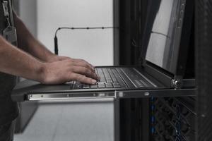 Close up on Data Center Engineer hands Using keyboard on a supercomputer Server Room Specialist Facility with Male System Administrator Working with Data Protection Network for Cyber Security. photo