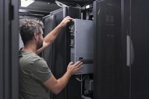 IT engineer working In the server room or data center The technician puts in a rack a new server of corporate business mainframe supercomputer or cryptocurrency mining farm. photo