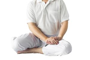 Men in white clothes sit with their hands clasped on their knees against a white backdrop. photo