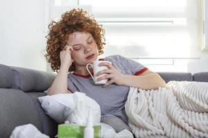 mujer joven deprimida molesta tendida en el sofá sintiendo fuerte dolor de cabeza migraña, adolescente cansada y soñolienta niña exhausta descansando tratando de dormir después de la tensión nerviosa y el estrés, concepto de somnolencia foto