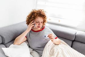 Sick woman calling health center for potential Coronavirus infection. Young woman with fever worried about her health. photo