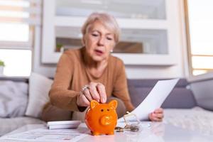 Senior woman doing finances at home. Senior woman with calculator and counting euro money at home. Business, savings, annuity insurance, age and people concept photo