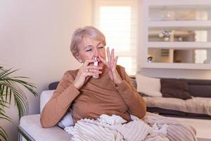 Senior Woman is having allergies and she is using nasal spray to help herself. Elder woman using nasal spray. Nasal spray to help a cold. Sick with a rhinitis woman dripping nose applies nasal spray photo