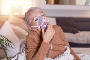 Sick elderly woman making inhalation, medicine is the best medicine. Ill senior woman wearing an oxygen mask and undergoing treatment. Senior woman with an inhaler photo