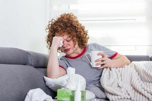 resfriado y gripe. retrato de una mujer enferma resfriada, sintiéndose enferma y estornudando en una toallita de papel. primer plano de una hermosa niña malsana cubierta de manta limpiándose la nariz. concepto de salud. alta resolución foto