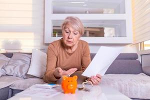 savings, money, annuity insurance, retirement and people concept - Senior woman hand putting coin into piggy bank. Mature woman Calculating Coin In The Piggybank photo