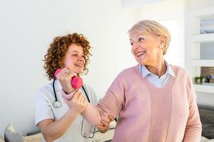 Senior woman after stroke at nursing home exercising with professional physiotherapist. Elder woman returning to good health. physiotherapist nurse helping an elderly women physical rehabilitation photo