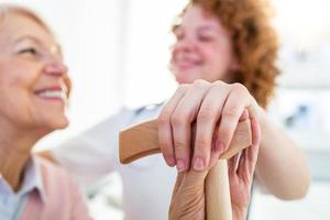 primer plano de la persona que toca la mano de la mujer mayor. concepto de asistencia domiciliaria. anciana mano sosteniendo la mano del joven cuidador en el hogar de ancianos. médico geriátrico o concepto de geriatra. foto