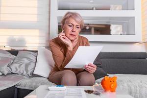 Senior woman doing finances at home. Senior woman with calculator and counting euro money at home. Business, savings, annuity insurance, age and people concept photo