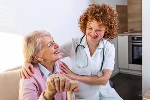 Happy patient is holding caregiver for a hand while spending time together. Elderly woman in nursing home and nurse. Aged elegant woman at nursing home photo