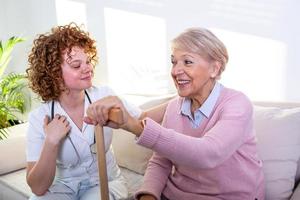 estrecha relación positiva entre el paciente mayor y el cuidador. feliz anciana hablando con un amable cuidador. joven bonita cuidadora y mujer mayor feliz foto