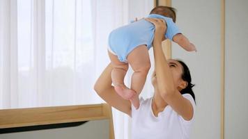 joven madre con su pequeño bebé jugando en la cama en casa. foto