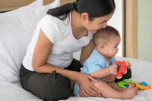 Asian mother taking care of newborn baby in a bedroom. photo