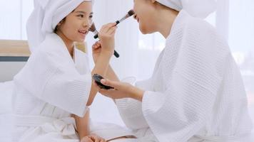 Mother with little daughter in bathrobes doing beauty treatment together in bedroom. photo