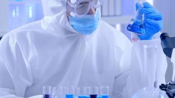 Scientist in PPE suite doing some research checking a liquid in a test tube at laboratory. photo