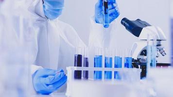 Scientist in PPE suite doing some research checking a liquid in a test tube at laboratory. photo