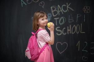 niño feliz con manzana y dibujo de regreso a la escuela en segundo plano foto