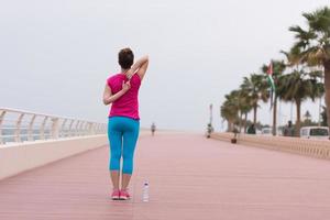 mujer estirándose y calentándose en el paseo marítimo foto