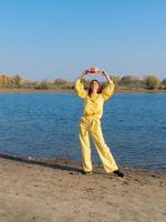 Woman in yellow clothes with red hat posing by the lake in autumn photo