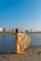 Woman in yellow clothes and a transparent cape posing by the lake. Positive lifestyle photo