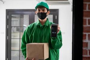 Deliveryman standing and holding smartphone and parcel box photo