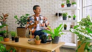 An old man sitting in a living room decorated with flower pots. photo